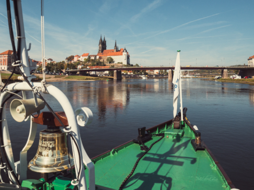 Weinstraße WEISSE Flotte Ein Dampfer fährt stromab auf der Elbe. Gleich erreicht er die Station Meißen. Voraus ist die alte Straßenbrücke zu sehen. links dahinter die Albrechtsburg in Meißen. Der Himmel ist blau, kein Wölkchen stört. Die Elbe fließt ruhig, es ist also auch nicht windig.
