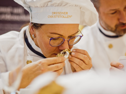 Eine Frau in Bäckerkleidung riecht an einem Stück Stollen.